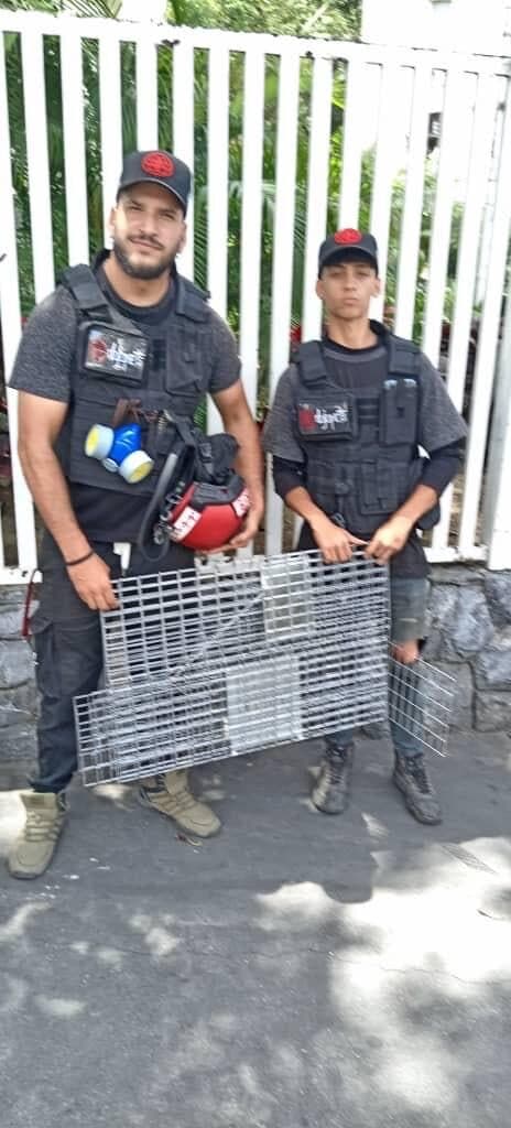 Dos rescatistas sostienen una de las jaulas trampa entregadas