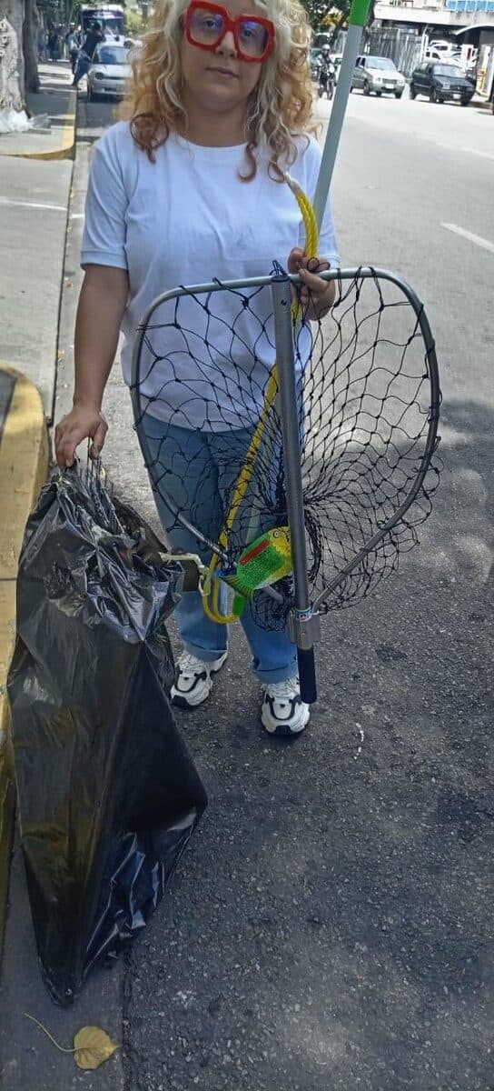 Voluntaria trasladando una jaula trampa por la calle